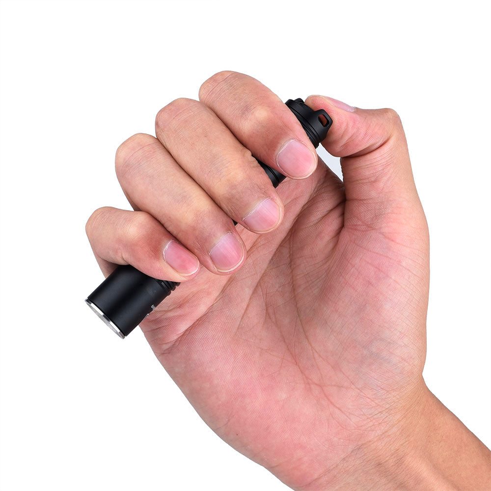Fitorch EC10 V2.0 held in one hand with a thumb on the tail switch