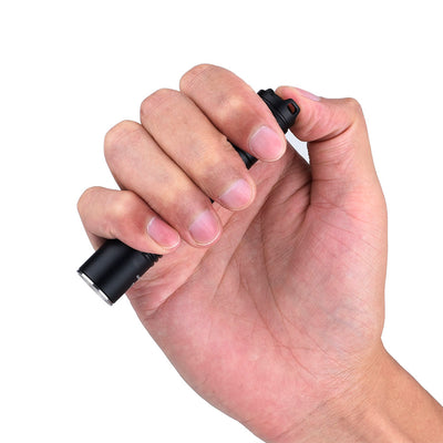 Fitorch EC10 V2.0 held in one hand with a thumb on the tail switch
