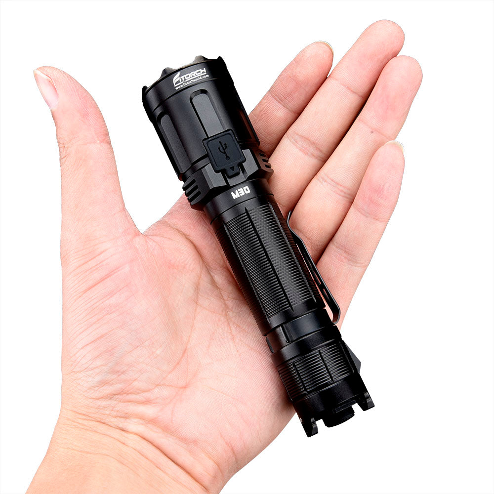 Fitorch M30 black tactical flashlight resting in a palm to demonstrate its size